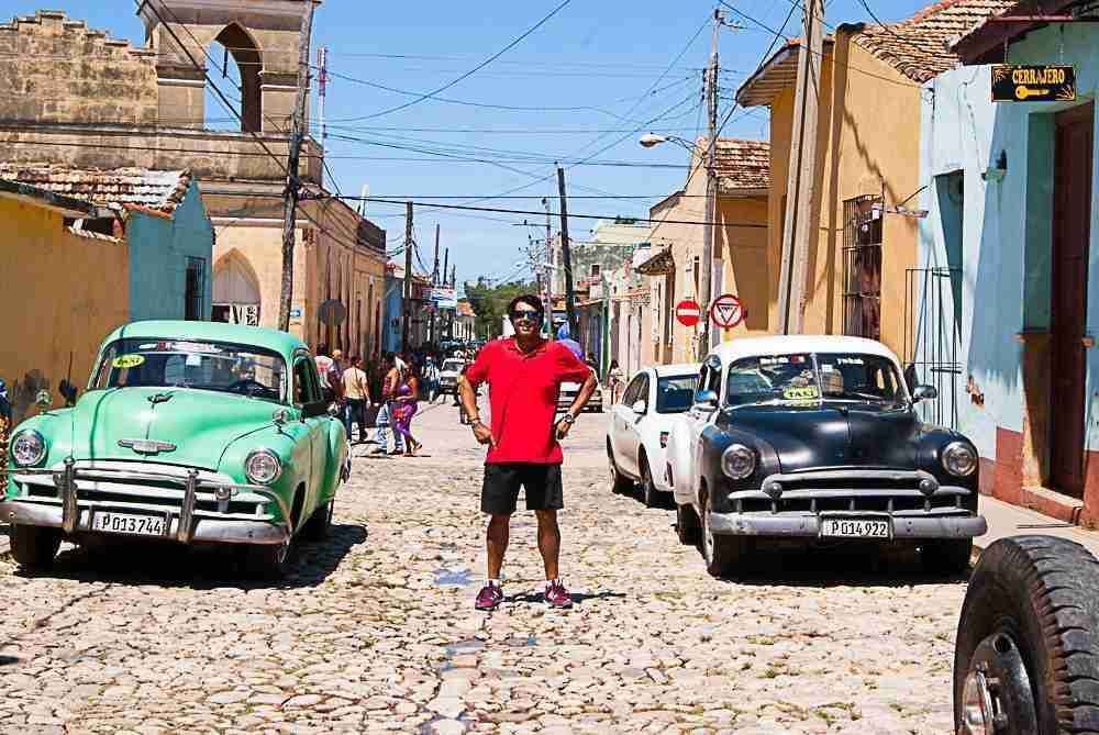 Javi posando en las calles de trinidad junto a vehículos clasicos