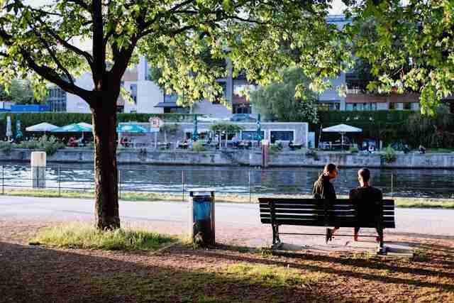 Pareja sentada en un banco cerca de rio en zona de Charlottenburg