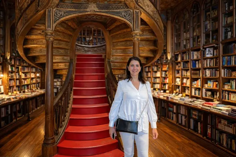 icónica escalera roja de madera tallada de la Librería Lello en Oporto, destacando su arquitectura neogótica y vitrales superiores.