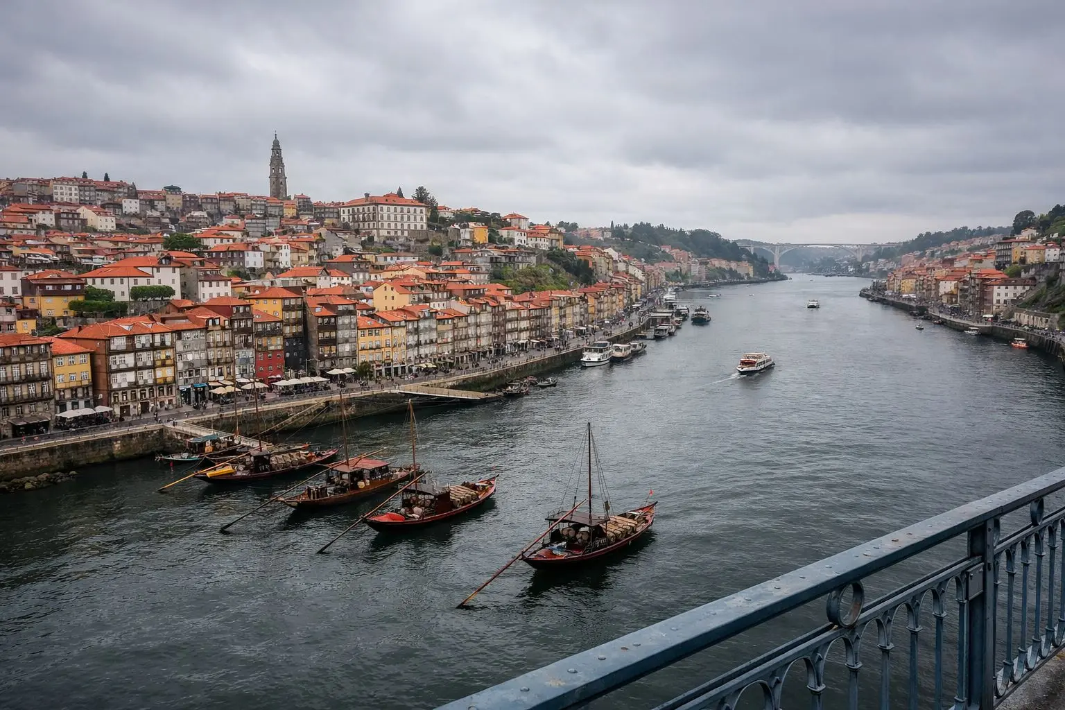 Vista panorámica del Cais da Ribeira y el río Duero en Oporto bajo un cielo nublado, resaltando la arquitectura tradicional y los barcos rabelos.