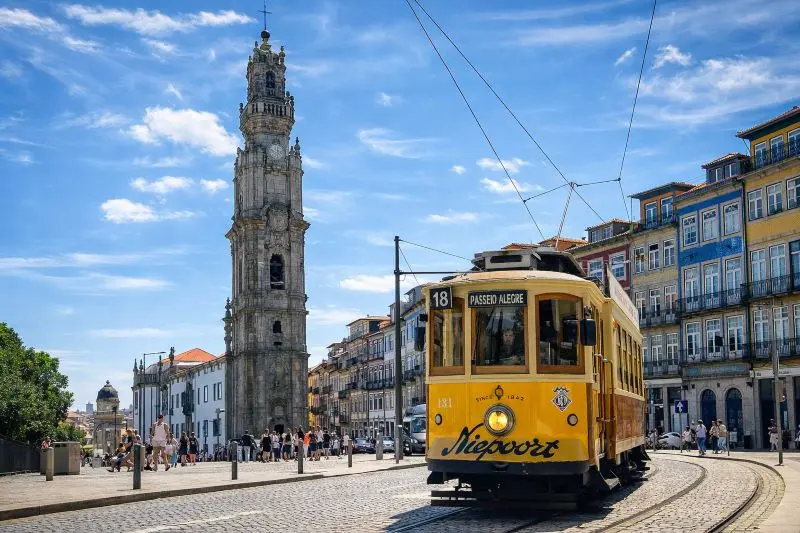 Tranvía clásico pasando frente a la Torre de los Clérigos en Oporto en un día soleado