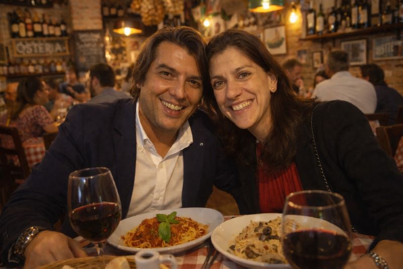Pareja brindando con vino tinto en una osteria, una experiencia auténtica para comer en la Toscana.