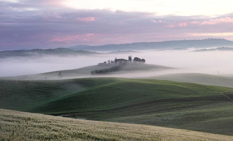 paisaje Val d'Orcia Toscana amanecer cipreses colinas niebla