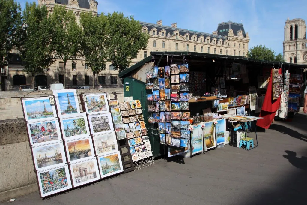 Vendedores de libros bouquinistes en el Quai Saint-Michel con cajas verdes y Notre-Dame al fondo
